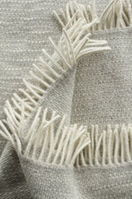Textured fabric with white fringe details on a neutral background